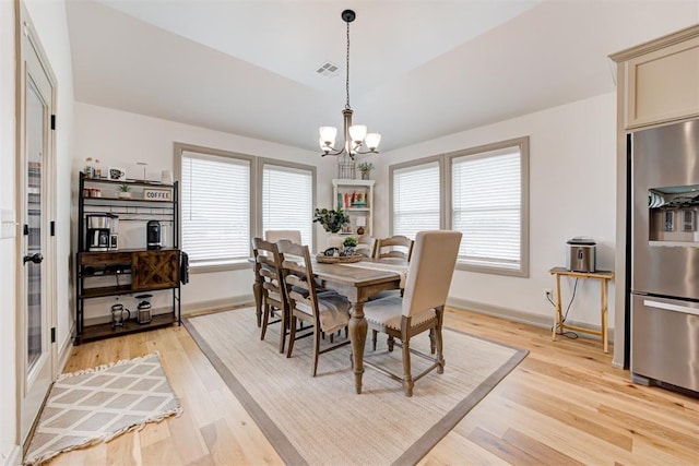 dining area featuring visible vents, baseboards, light wood-type flooring, and a chandelier