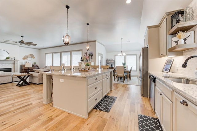 kitchen featuring light wood-style flooring, a breakfast bar area, appliances with stainless steel finishes, ceiling fan with notable chandelier, and a sink