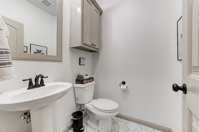 bathroom featuring a sink, visible vents, toilet, and baseboards