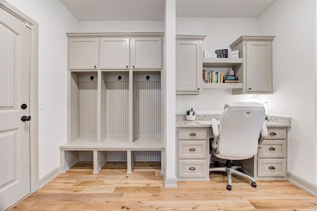 office area with built in study area, light wood finished floors, and baseboards