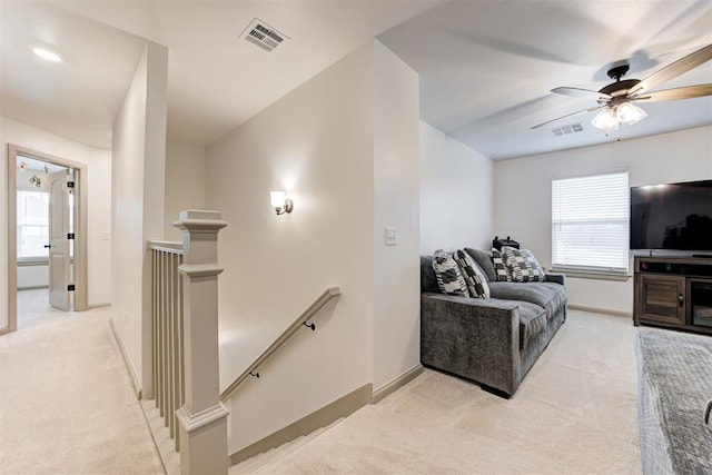 living area featuring light carpet, baseboards, a ceiling fan, and visible vents