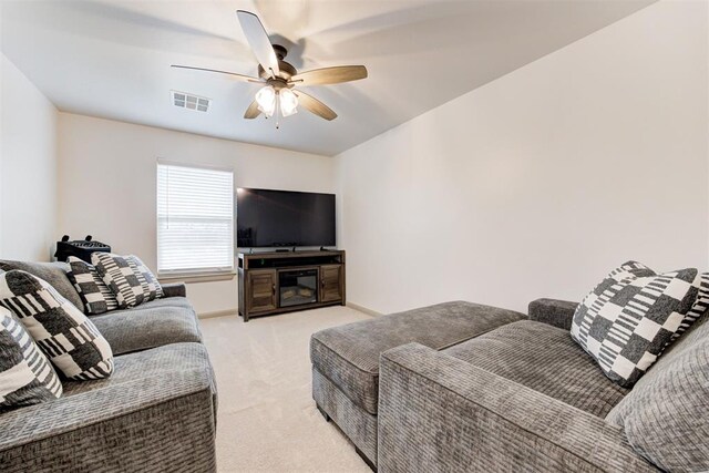 living room featuring baseboards, visible vents, light colored carpet, and a ceiling fan