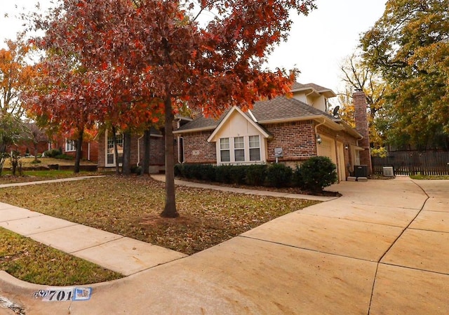 obstructed view of property with a garage, concrete driveway, a chimney, fence, and brick siding