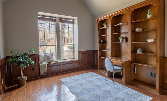 office area featuring lofted ceiling, a wainscoted wall, and light wood-style flooring