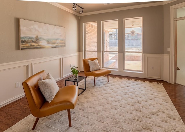 living area with a decorative wall, a wainscoted wall, ornamental molding, light wood finished floors, and rail lighting