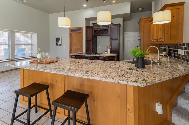 kitchen featuring light stone counters, brown cabinets, a sink, and a peninsula