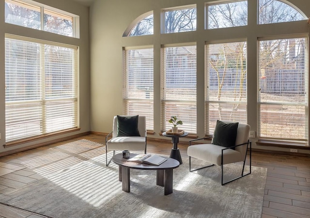 living area with a high ceiling, a wealth of natural light, and wood finished floors