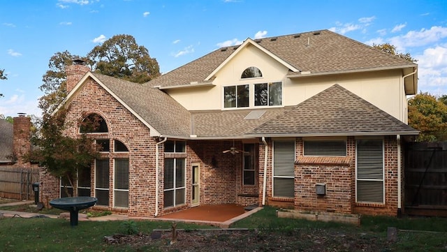 back of house with brick siding, a shingled roof, fence, a chimney, and a patio area