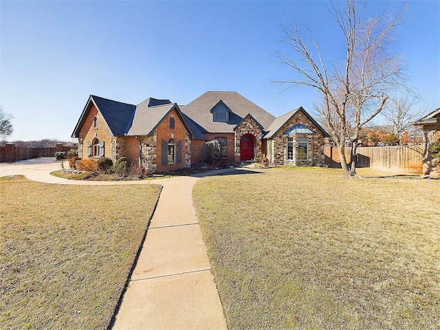 view of front of house with a front yard, brick siding, and fence