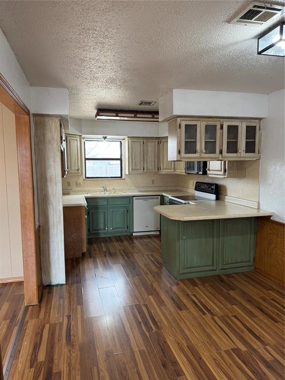 kitchen with a peninsula, range with electric cooktop, light countertops, dishwasher, and glass insert cabinets