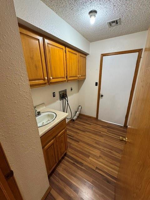 clothes washing area with cabinet space, visible vents, dark wood-style floors, washer hookup, and electric dryer hookup