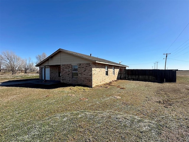 view of side of property with a yard, brick siding, and fence