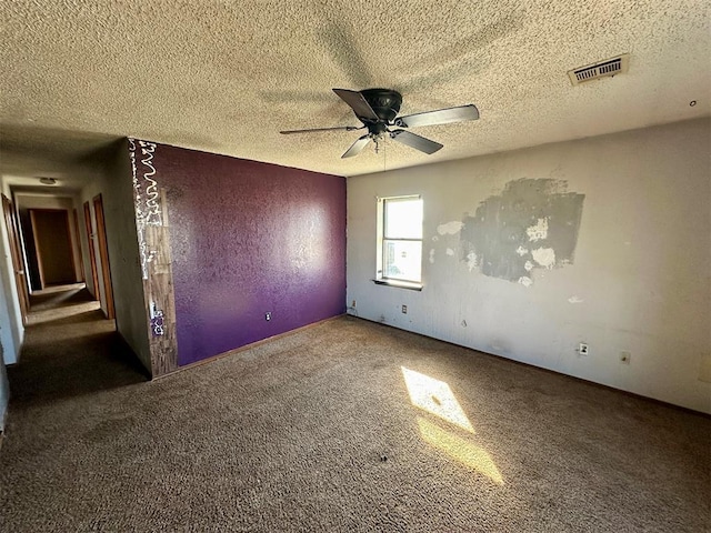 carpeted empty room featuring ceiling fan, visible vents, and a textured ceiling