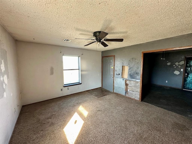 unfurnished bedroom with a ceiling fan, visible vents, a textured ceiling, and carpet flooring