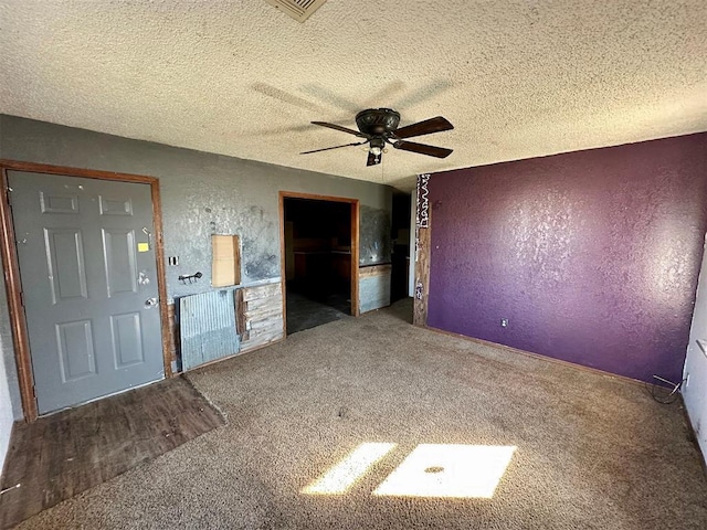 unfurnished room with carpet, a textured wall, a textured ceiling, and ceiling fan