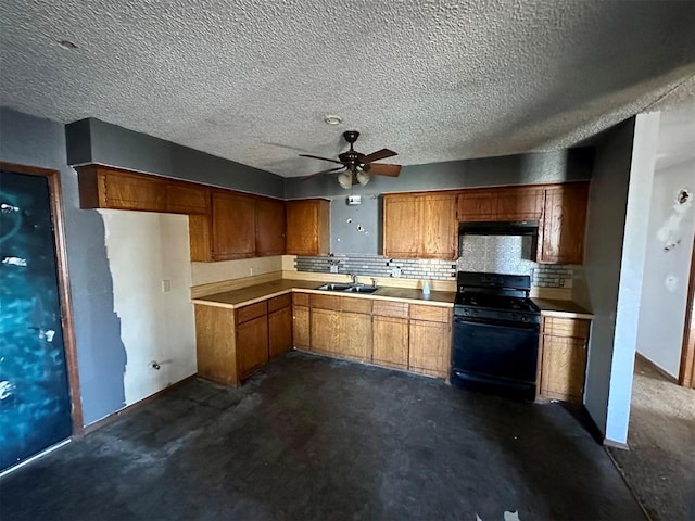 kitchen with black gas range, brown cabinets, a sink, light countertops, and backsplash