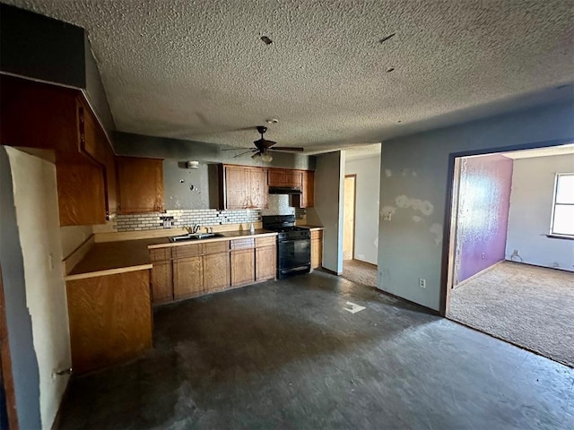 kitchen with tasteful backsplash, brown cabinets, black range with gas stovetop, light countertops, and a sink