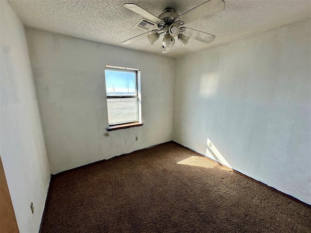 empty room with visible vents, a ceiling fan, dark colored carpet, and a textured ceiling