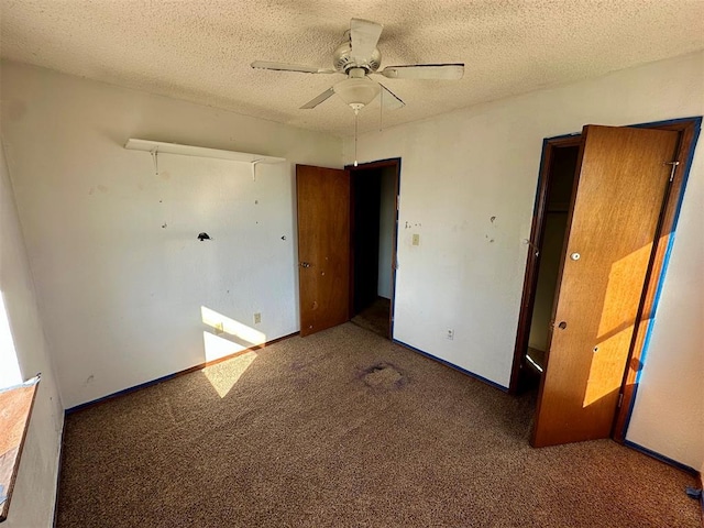 unfurnished bedroom with dark colored carpet, a closet, ceiling fan, a textured ceiling, and baseboards