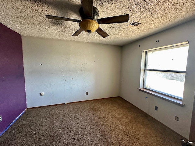 carpeted empty room with a textured ceiling, baseboards, visible vents, and a ceiling fan