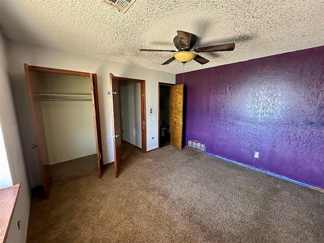 unfurnished bedroom featuring a textured ceiling, a textured wall, carpet floors, and visible vents