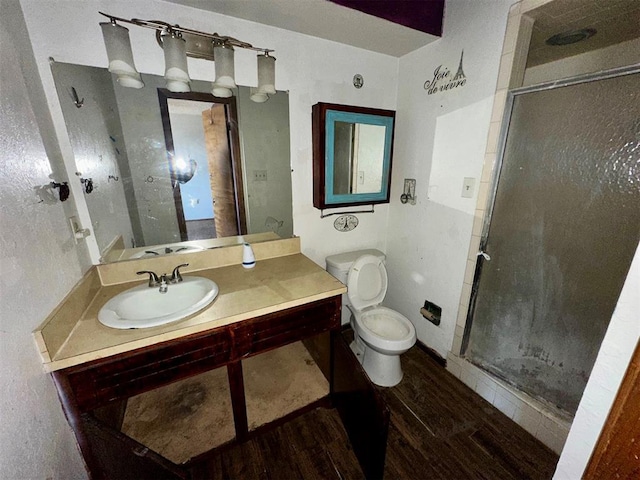 full bathroom with a stall shower, vanity, toilet, and wood finished floors