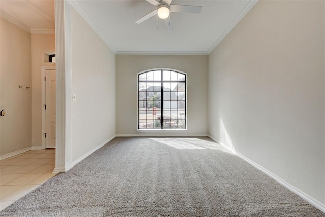 carpeted empty room with baseboards, ornamental molding, a ceiling fan, and tile patterned floors