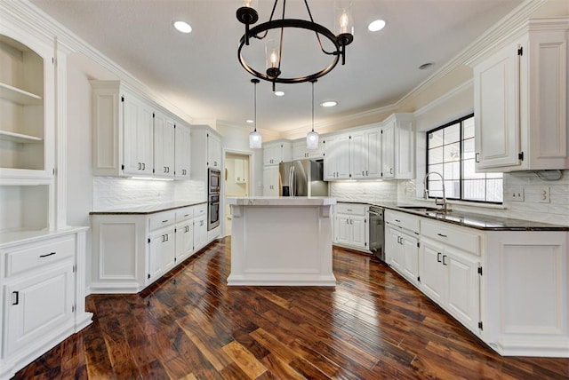 kitchen featuring stainless steel appliances, a sink, white cabinetry, a center island, and crown molding