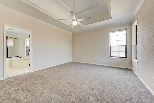 empty room featuring ceiling fan, baseboards, carpet, a raised ceiling, and crown molding