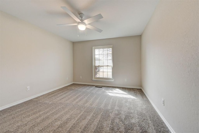 carpeted spare room with visible vents, a ceiling fan, and baseboards