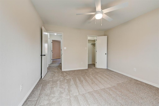 unfurnished bedroom with ceiling fan, carpet floors, a walk in closet, and baseboards