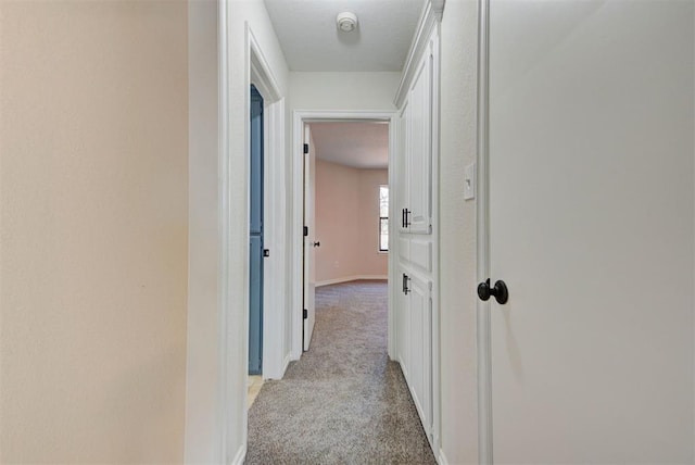 hallway with light colored carpet and baseboards