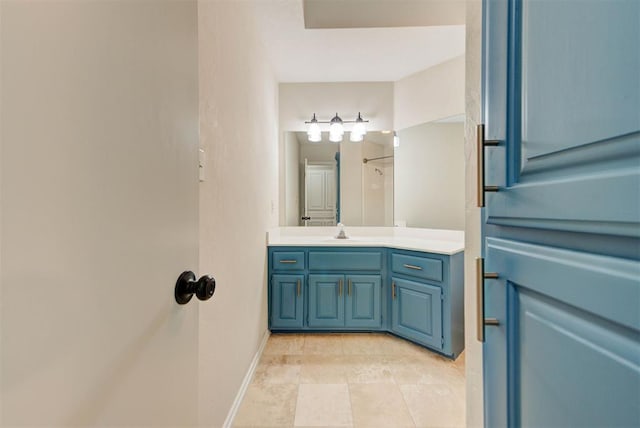 bathroom with a shower, vanity, and baseboards