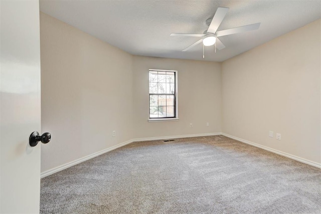 empty room with carpet floors, a ceiling fan, and baseboards