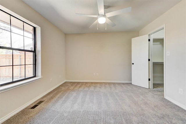 carpeted spare room with baseboards, visible vents, and a ceiling fan