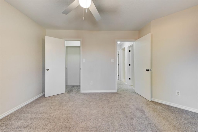 unfurnished bedroom with a spacious closet, carpet, and baseboards