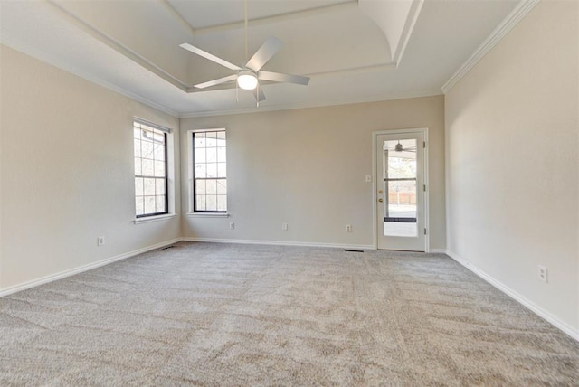 unfurnished room with baseboards, a ceiling fan, a tray ceiling, crown molding, and carpet floors