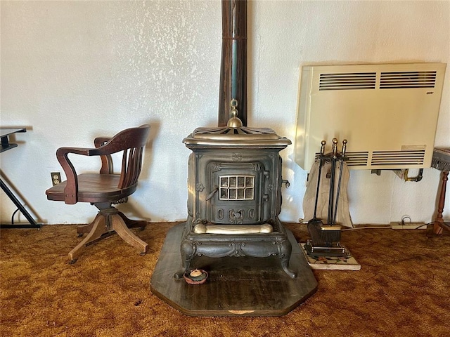 interior details with carpet, a wood stove, a textured wall, and heating unit