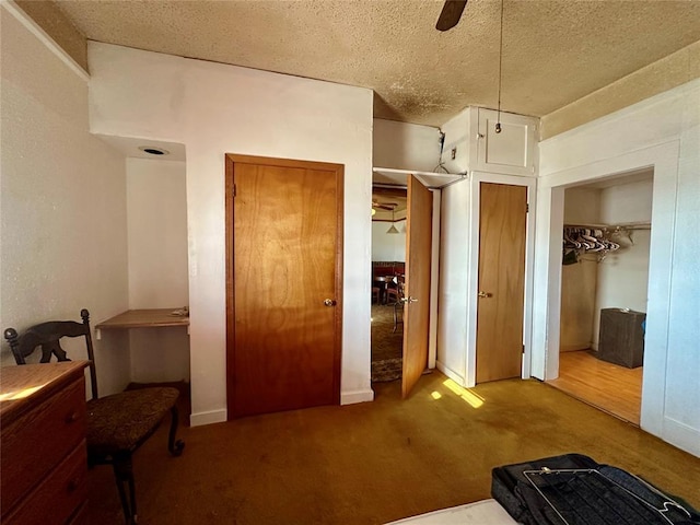 bedroom with carpet floors, two closets, ceiling fan, and a textured ceiling