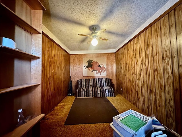 interior space featuring wood walls, carpet, ceiling fan, and a textured ceiling