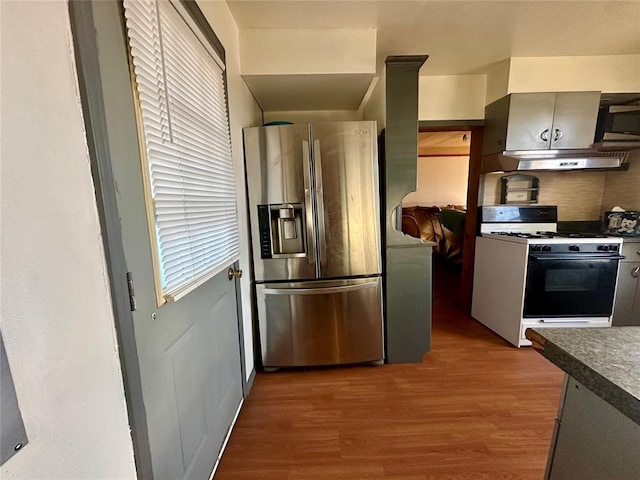 kitchen featuring dark countertops, gas range gas stove, stainless steel refrigerator with ice dispenser, and gray cabinetry