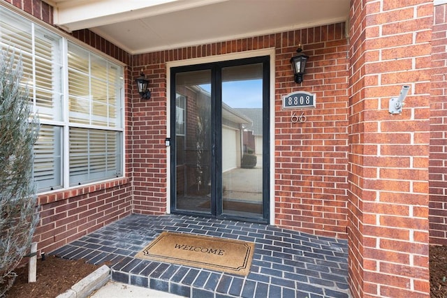 doorway to property featuring brick siding