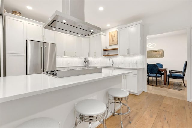 kitchen featuring light countertops, appliances with stainless steel finishes, island exhaust hood, and white cabinets