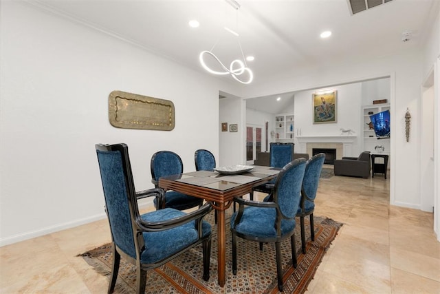 dining space with baseboards, built in features, visible vents, a fireplace, and a notable chandelier