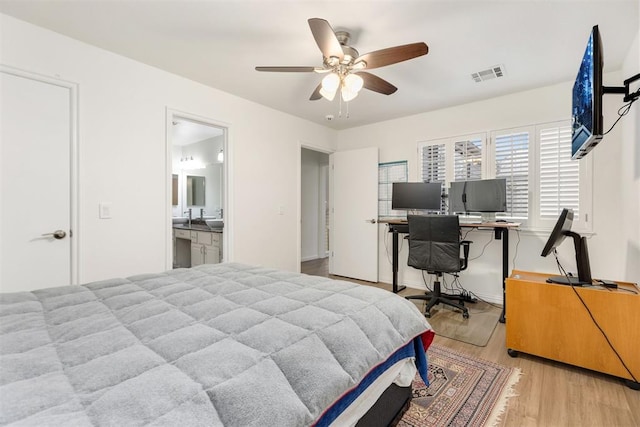 bedroom featuring a ceiling fan, visible vents, light wood-style flooring, and ensuite bathroom