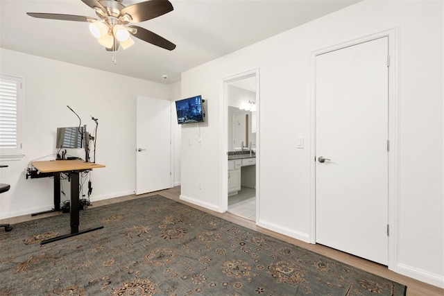 unfurnished bedroom featuring ensuite bathroom, ceiling fan, wood finished floors, and baseboards