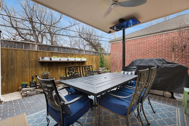 view of patio / terrace featuring ceiling fan, a fenced backyard, grilling area, an outdoor bar, and outdoor dining space