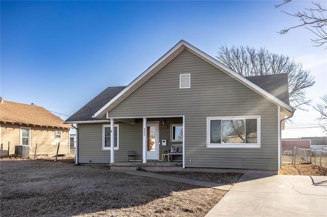 rear view of property featuring a porch, cooling unit, roof with shingles, and fence