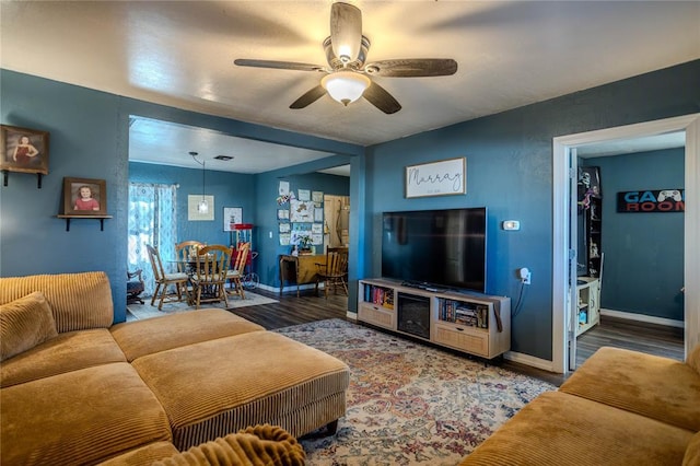 living area featuring wood finished floors, a ceiling fan, and baseboards