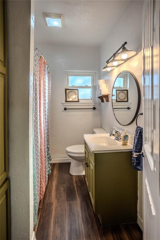 full bath featuring toilet, a shower with shower curtain, wood finished floors, vanity, and baseboards